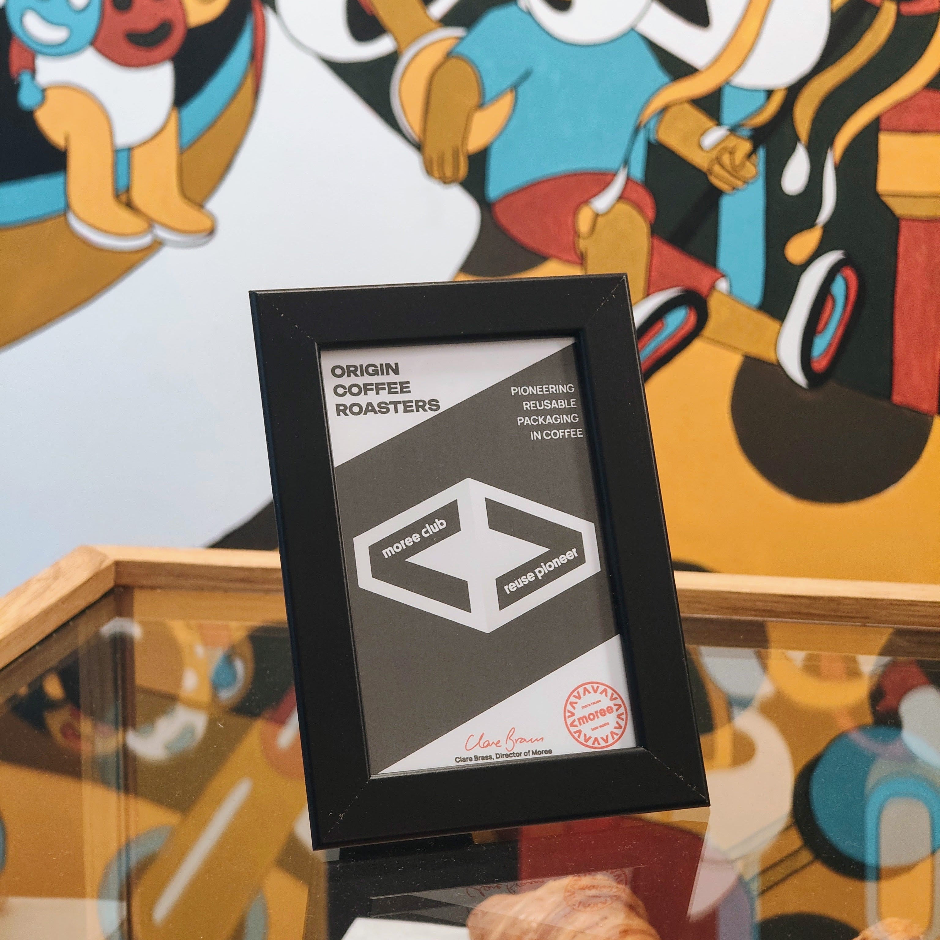 Framed coffee roaster label in front of a colorful abstract painting